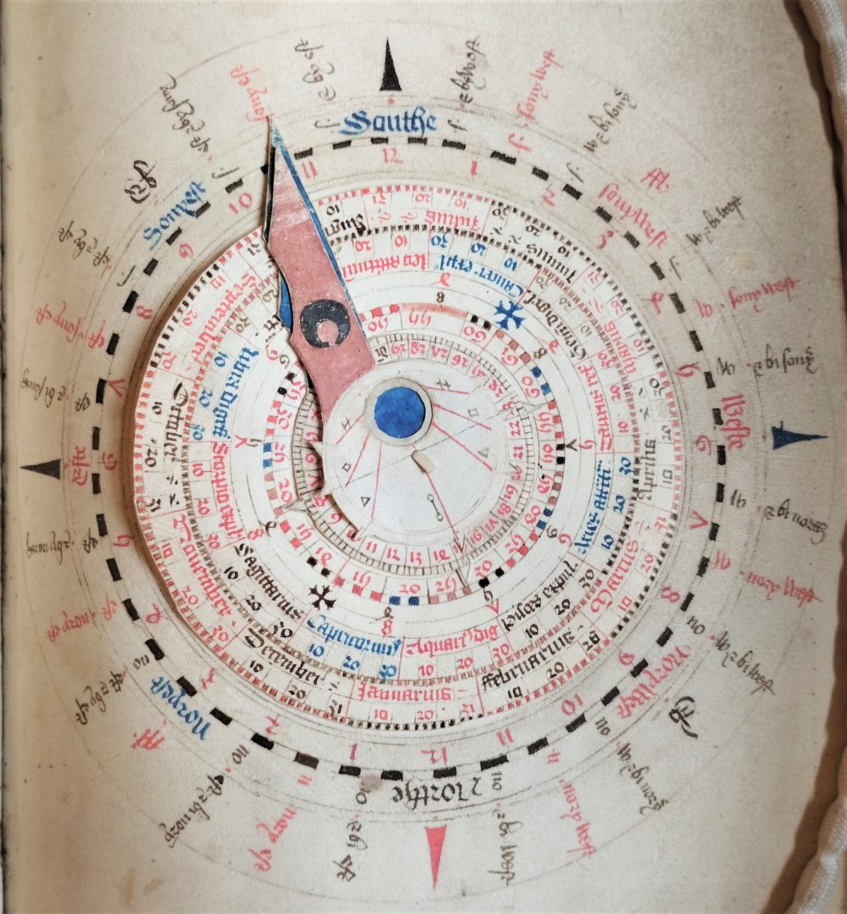 Hand drawn volvelle: an astronomical device, coloured in black, red, and blue, consisting of layered, rotating parts and dials.   