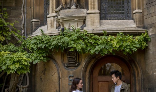 Two students standing at the entrance of S staircase (S starcase has wisteria creeping around the door)