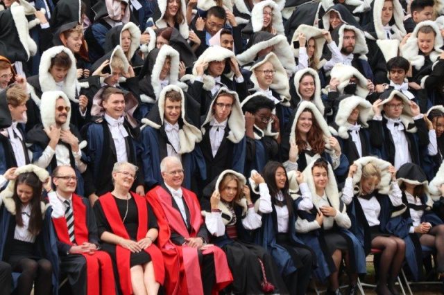 Students wearing the hoods of their gowns in a graduation photo