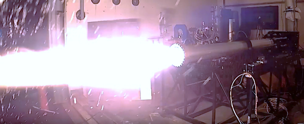 A rocket engine being tested, with flames firing out of the base of the engine