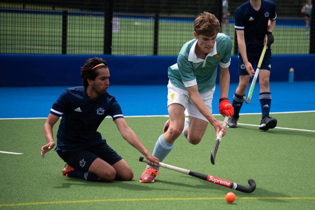 Two players playing hockey, one attempting a tackle on his knees
