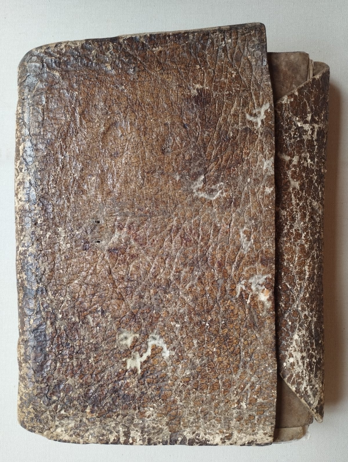 A worn grey leather folder, with sheets of parchment showing under the inner flap.