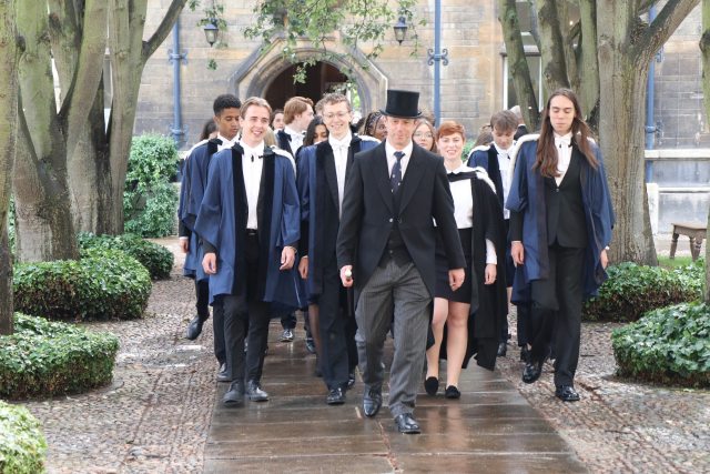 A graduation procession led by the Head Porter in a top hat