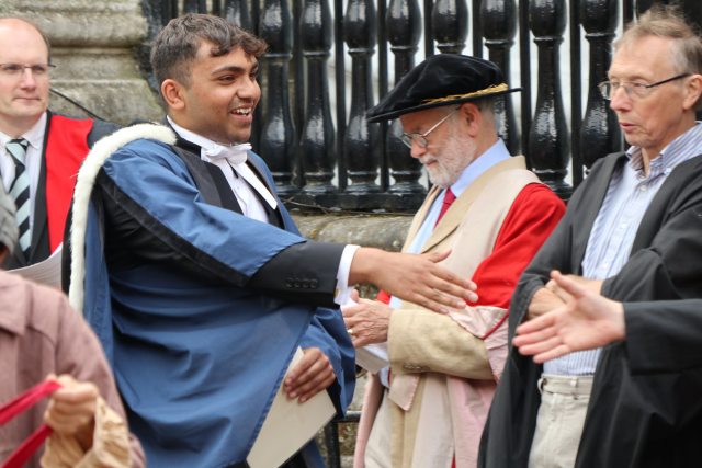 A graduate being congratulated by academics