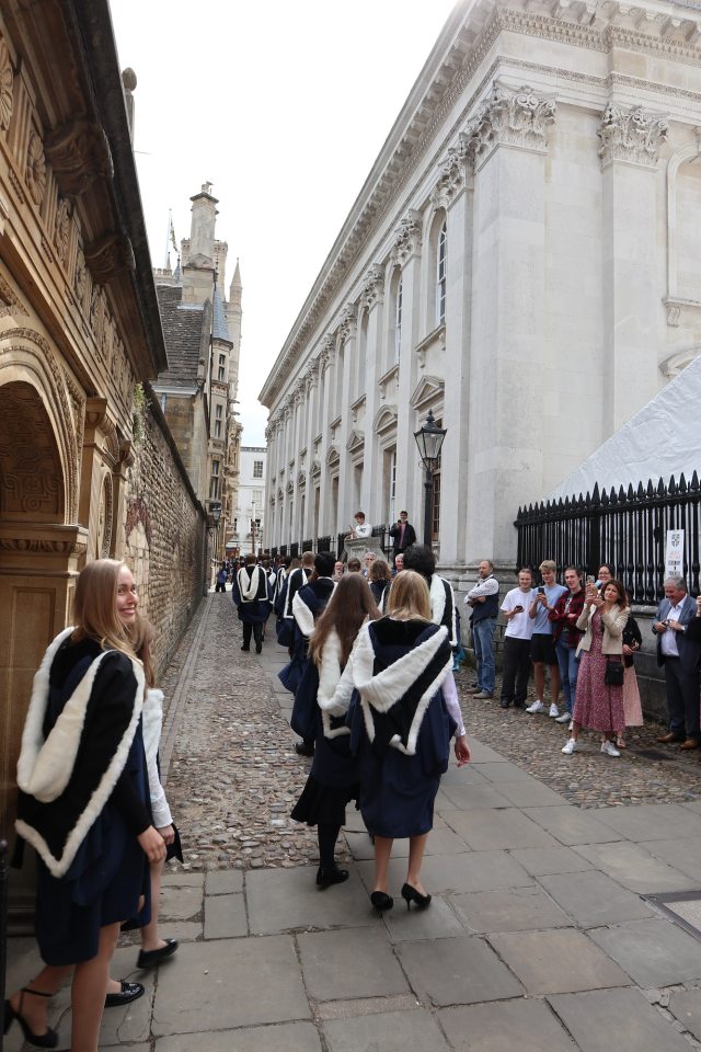 Graduands process along Senate House Passage watched by their loved ones
