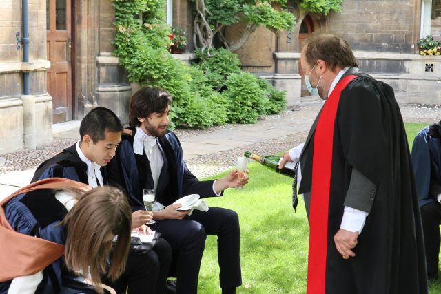 Graduates receiving a glass of champagne poured by a Fellow