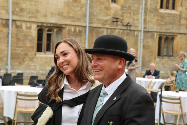 A female and a male in a bowler hat pose for a photo