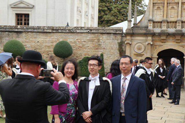 A man in a bowler hat takes a photograph of three people