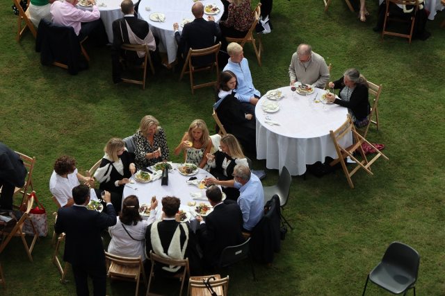 Tables of people dining and drinking on a lawn
