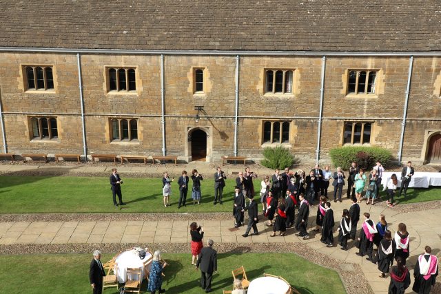 Graduands and Graduates process through Caius Court surrounded by family and friends